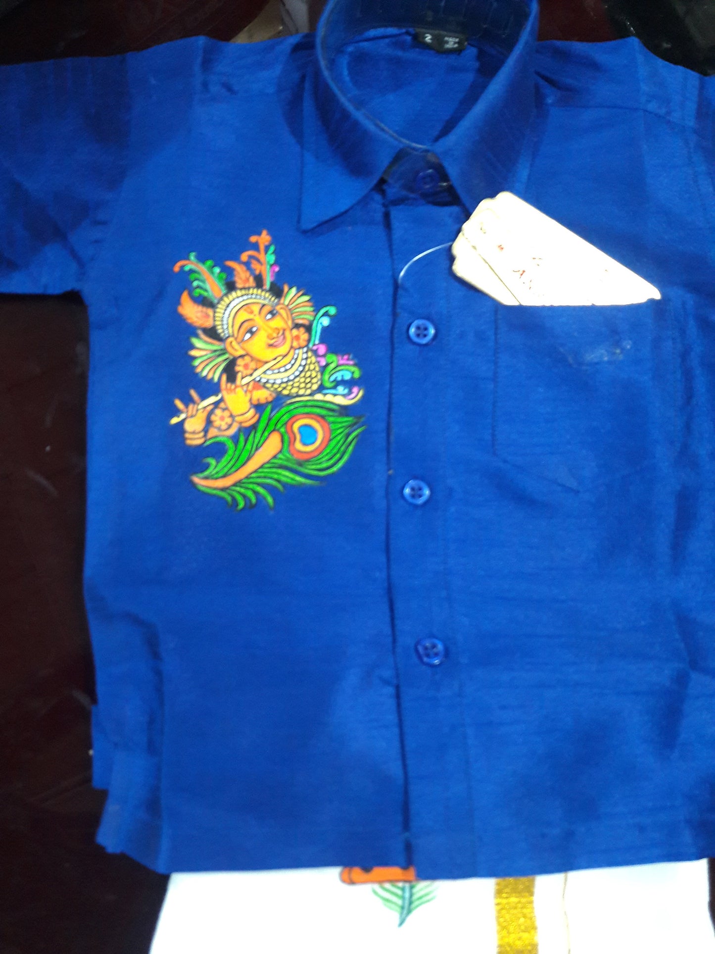 Krishna with peeli hand mural painting on blue kids shirt with peeli mundu